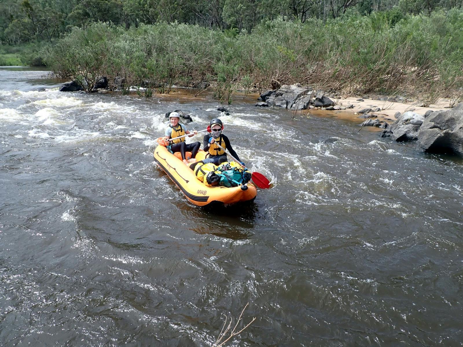 Tow people are paddling a raft in fast flowing water