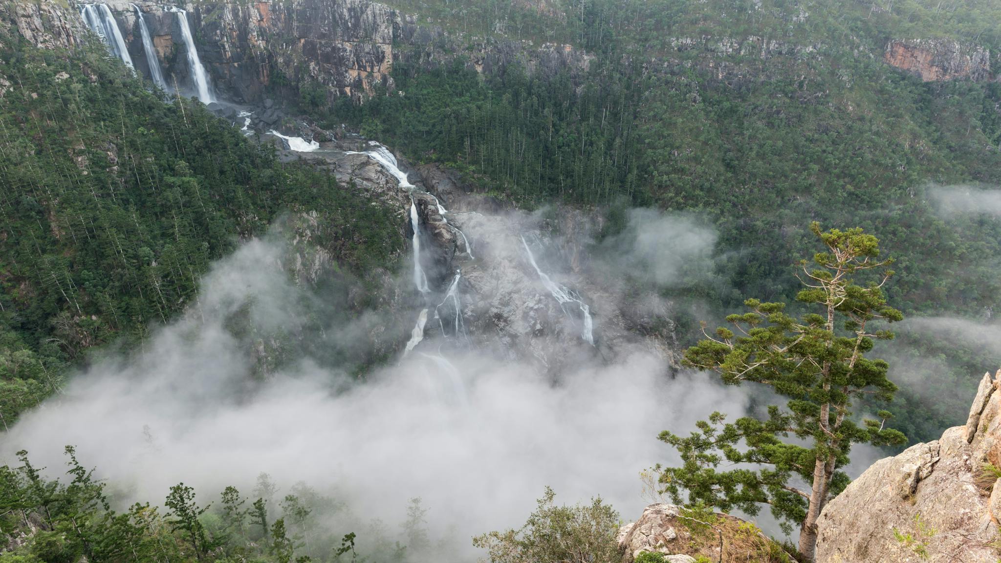 Water falls over rocky gorge, covered in cloud and mist surrounded by forest. Water falls over rocky gorge, covered in cloud and mist surrounded by forest.
