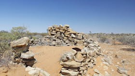 Ruins of rock walls on sandy dune.