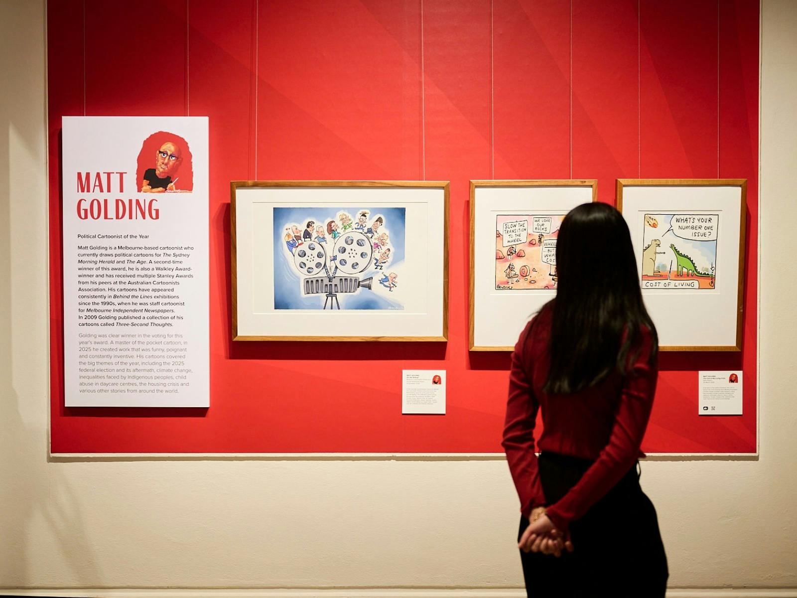 Woman views framer political cartoon in gallery.