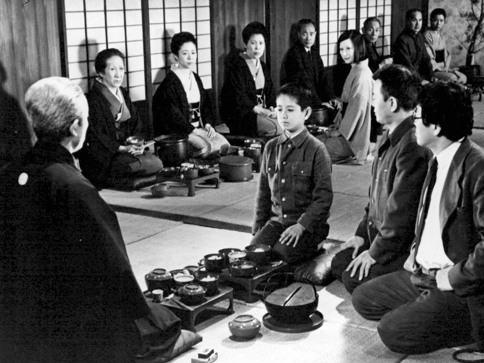 Black and white image of a child seated in the middle of a circle of adults