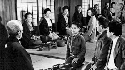 Black and white image of a child seated in the middle of a circle of adults