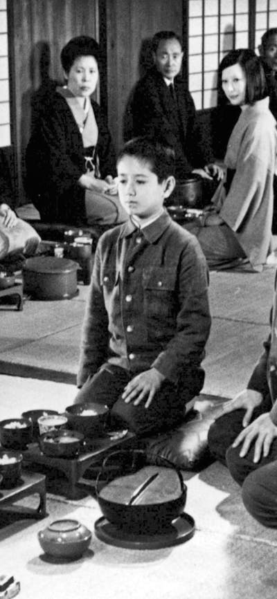 Black and white image of a child seated in the middle of a circle of adults
