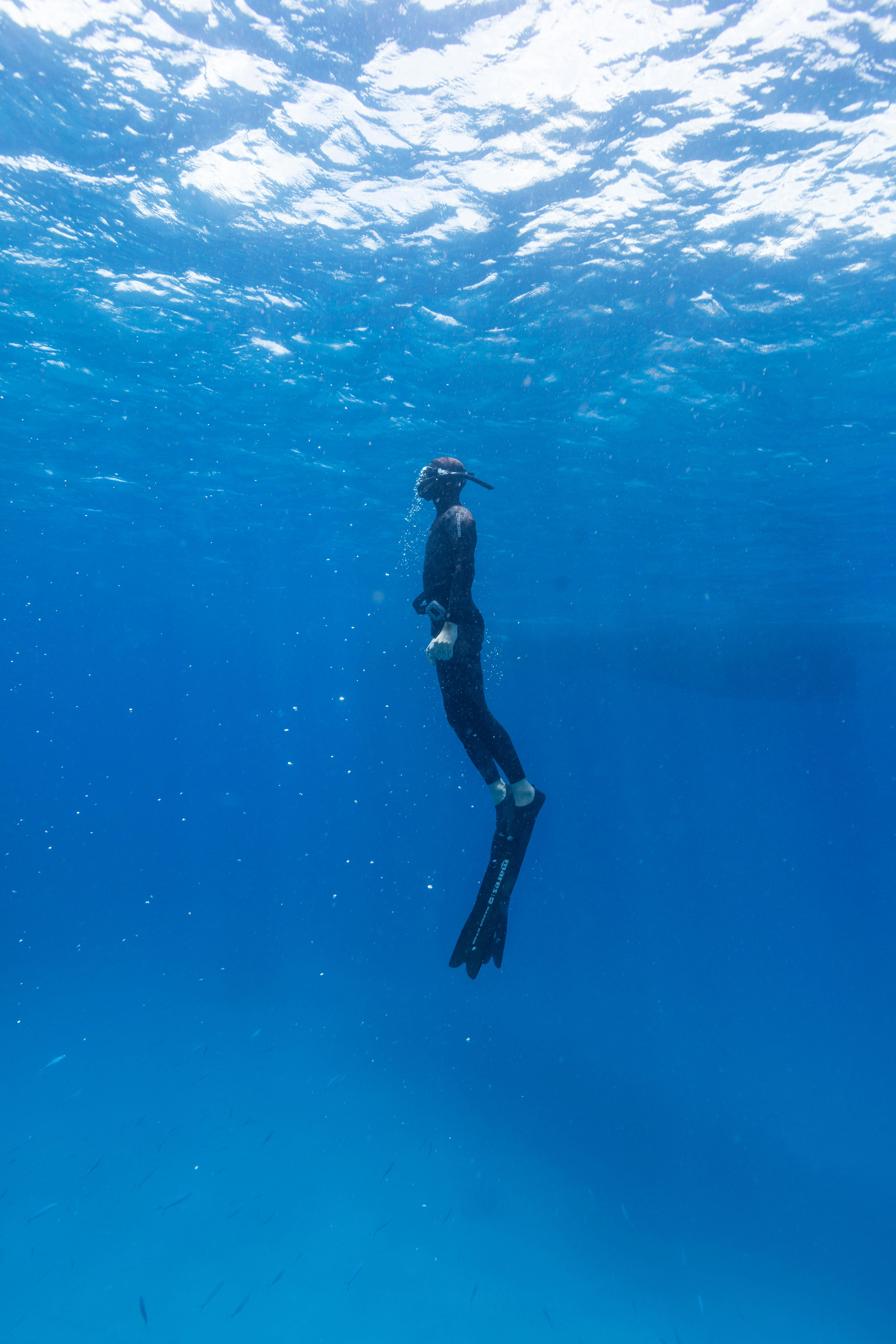 Male freediver surfacing from a deep dive in the ocean