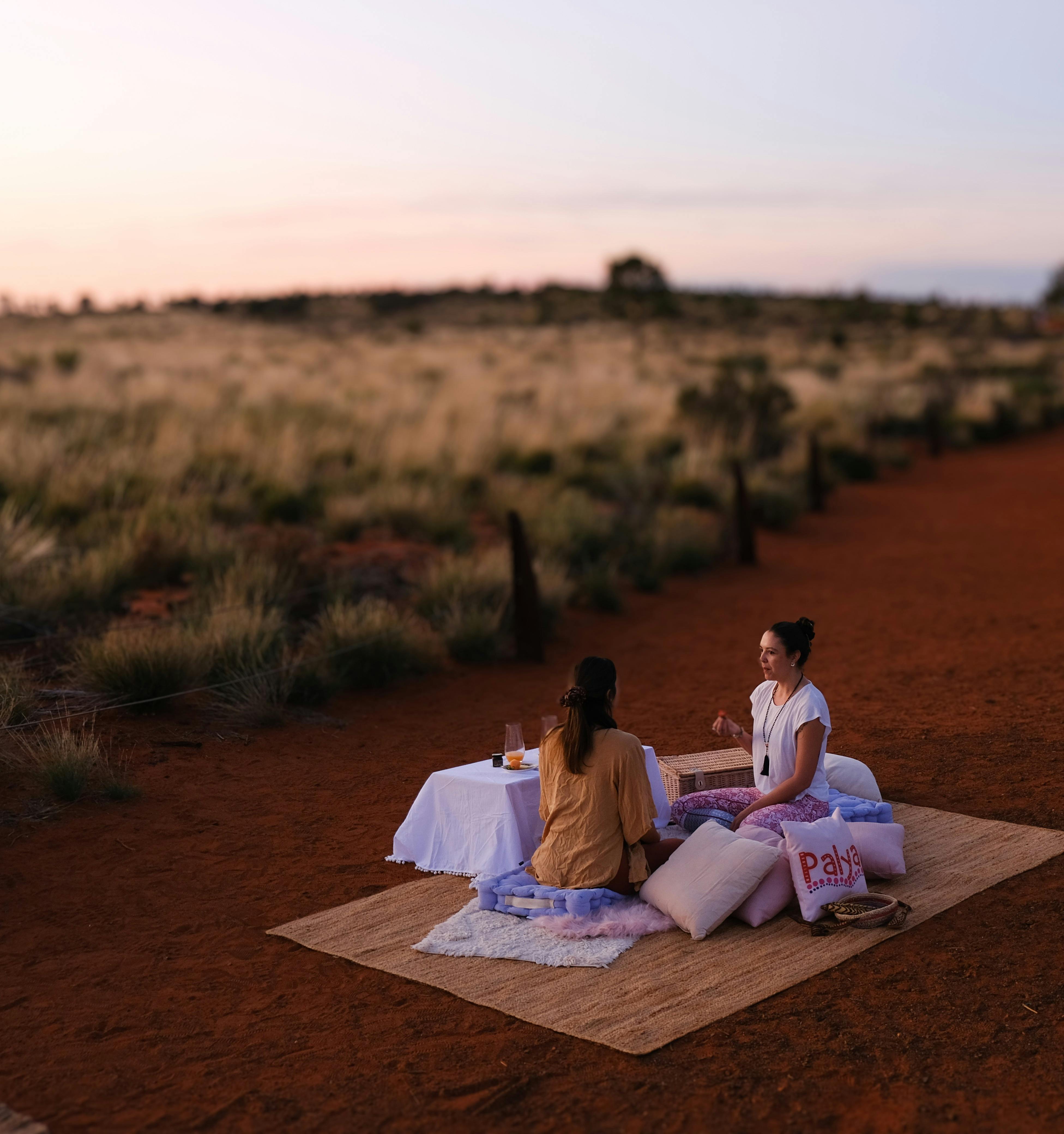 Two people sitting on the ground having a breakfast picnic