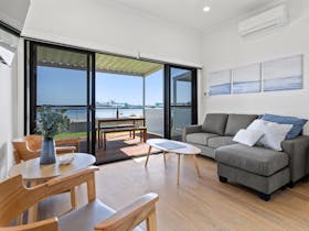 Interior lounge/dining area of Apartment 5, including lounge with chaise, artwork and view to beach.