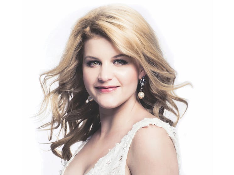 Blonde woman in white dress looking at camera