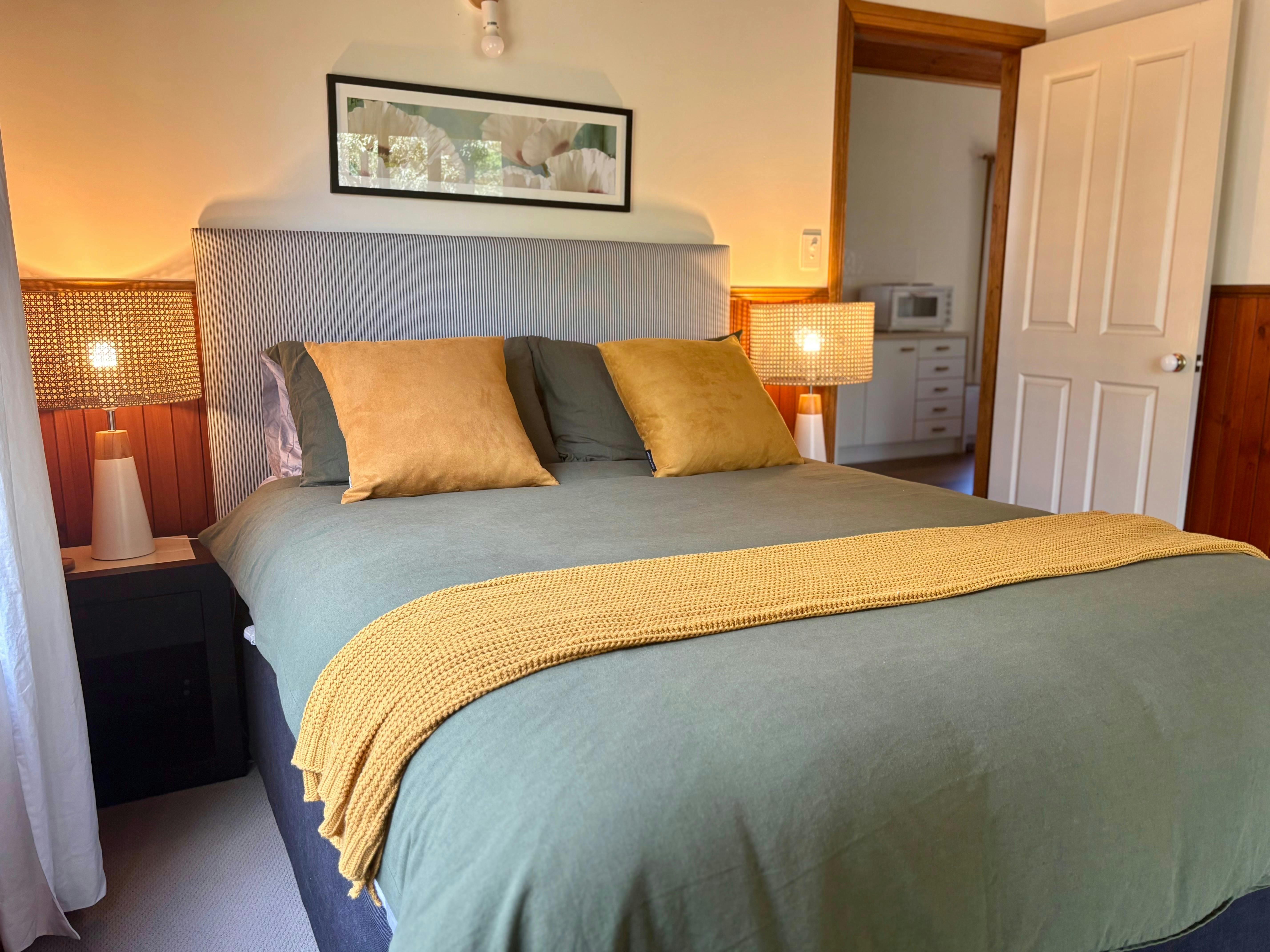 Bed with deluxe linen in a tree green with yellow cushions