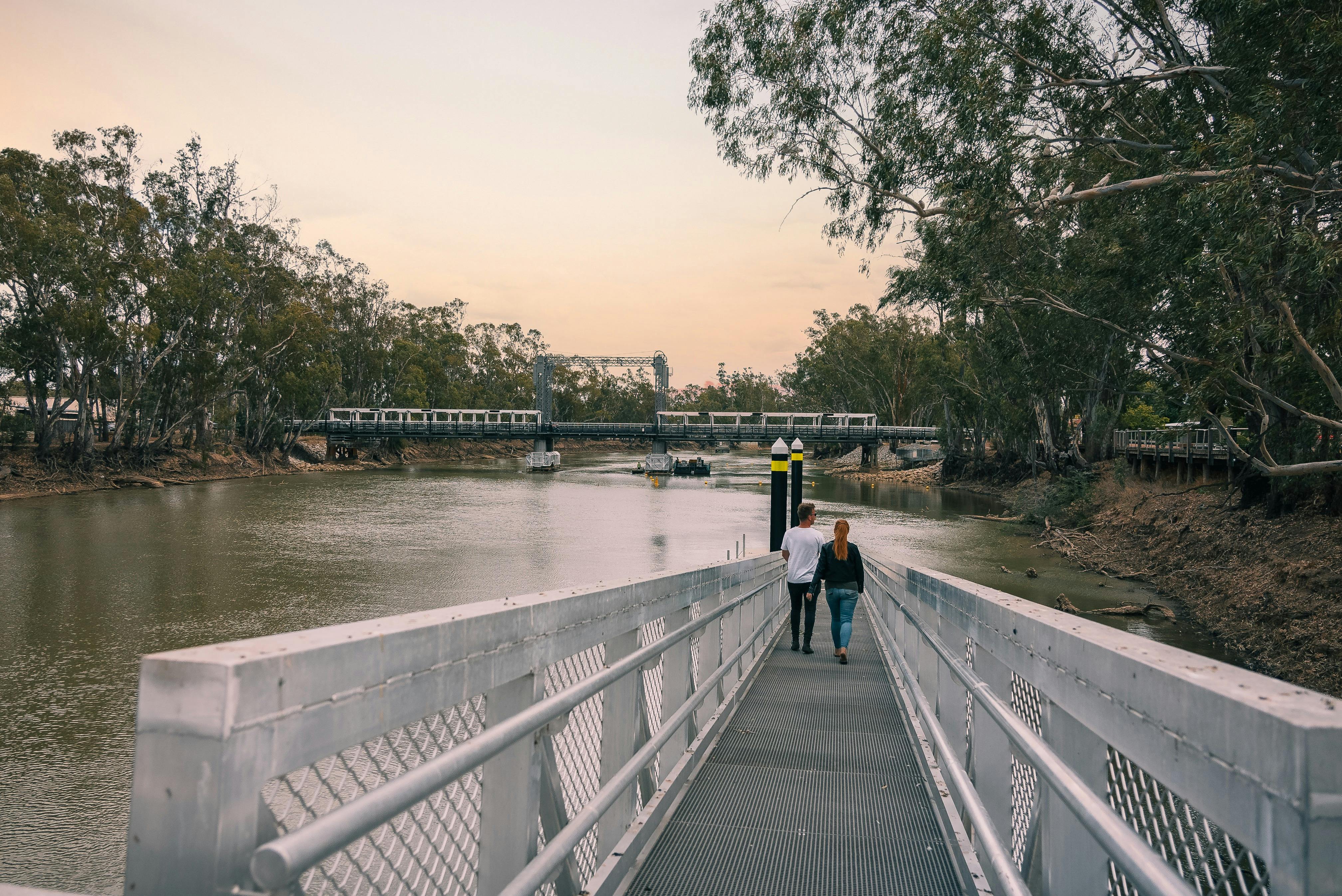 금속 산책로를 따라 강으로 걸어가는 커플