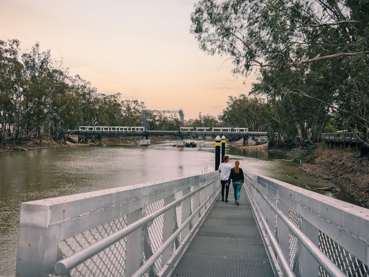 Couple walking down a metal walkway to the River