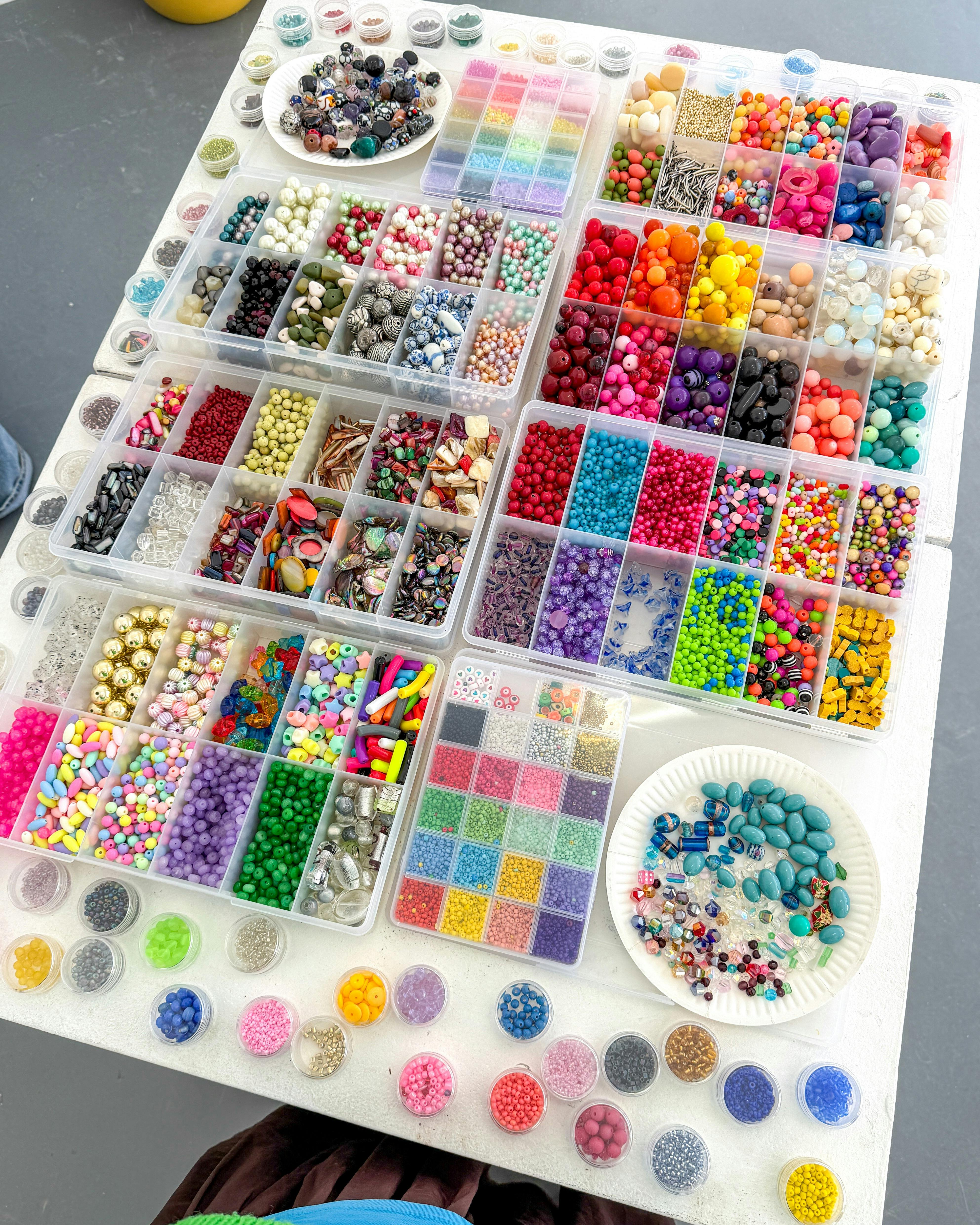 a table covered in containers holding lots of colourful second hand beads.