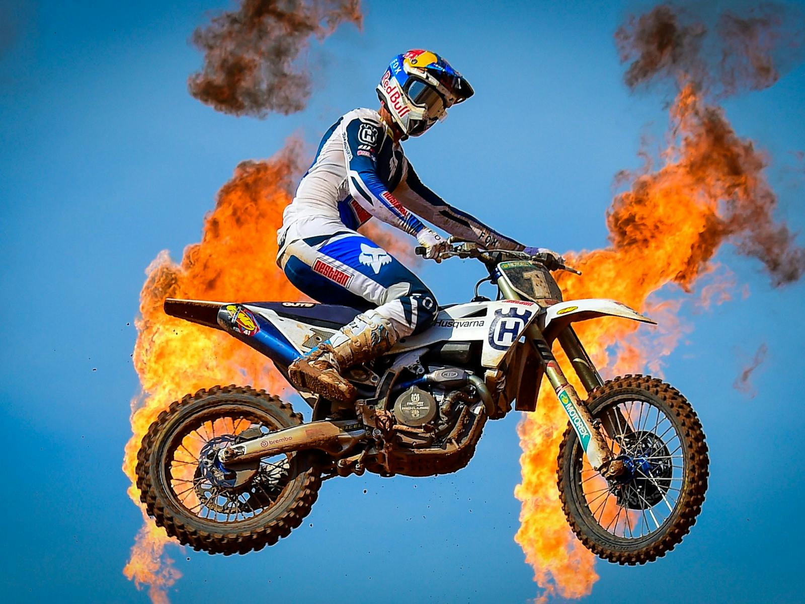 MXGP rider on bike jumping with flames behind