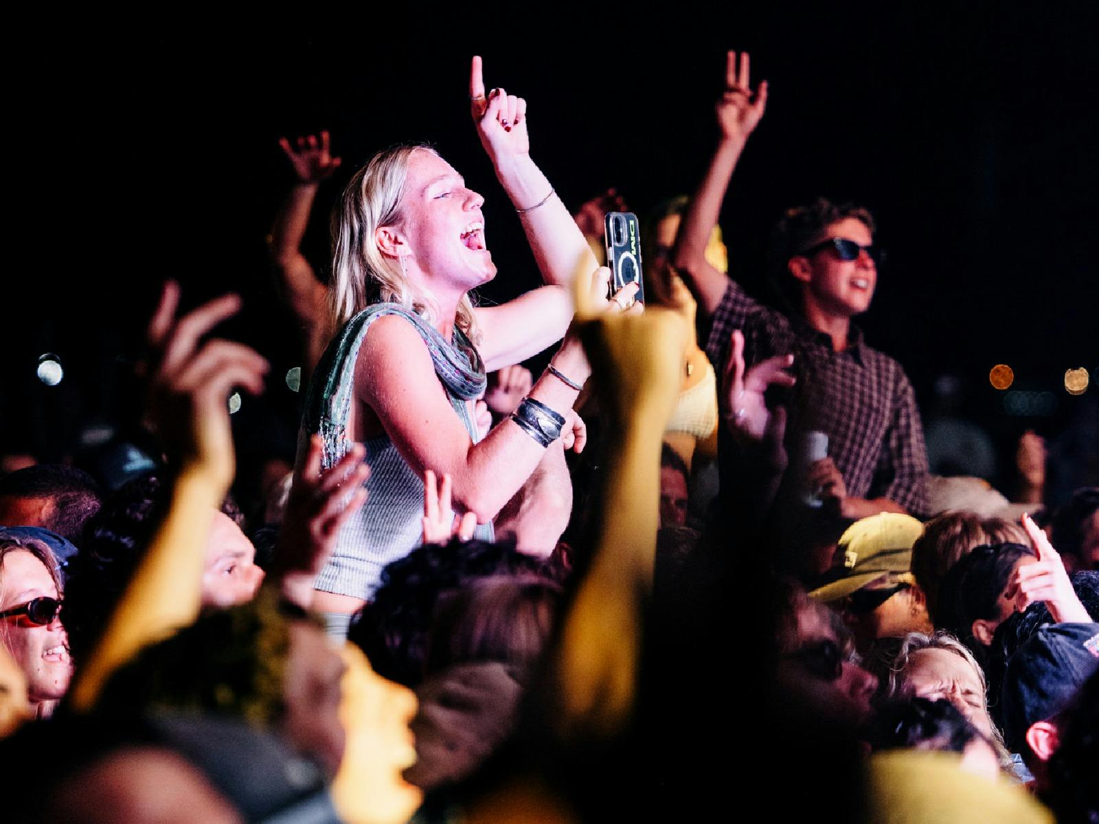 A group enthusiastically rocks out in a dimly lit concert venue