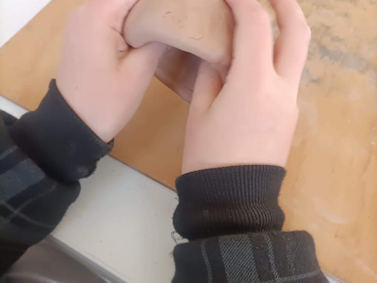 photo shows a child making a clay pot with their hands