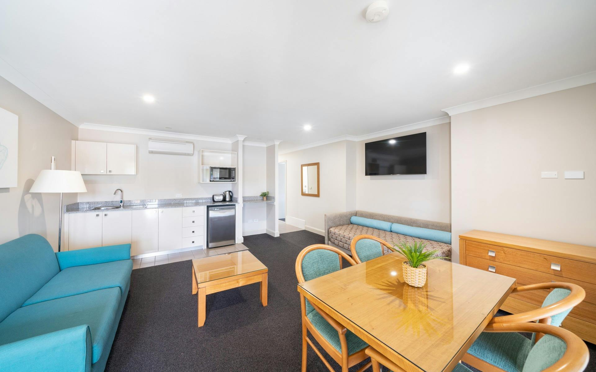 파란색 액센트로 장식된 완비된 주방과 식사 공간을 갖춘 세련된 라운지룸입니다.