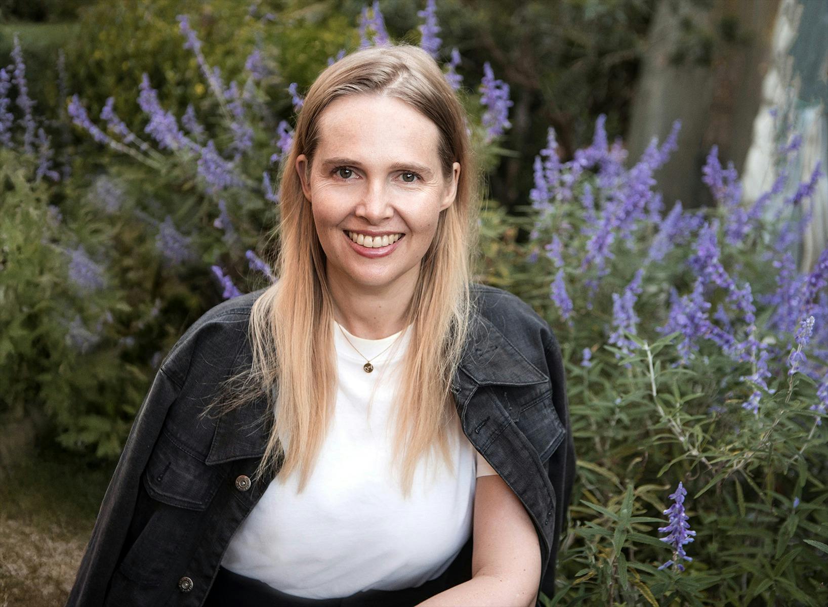 A woman smiling in front of a lavender bush