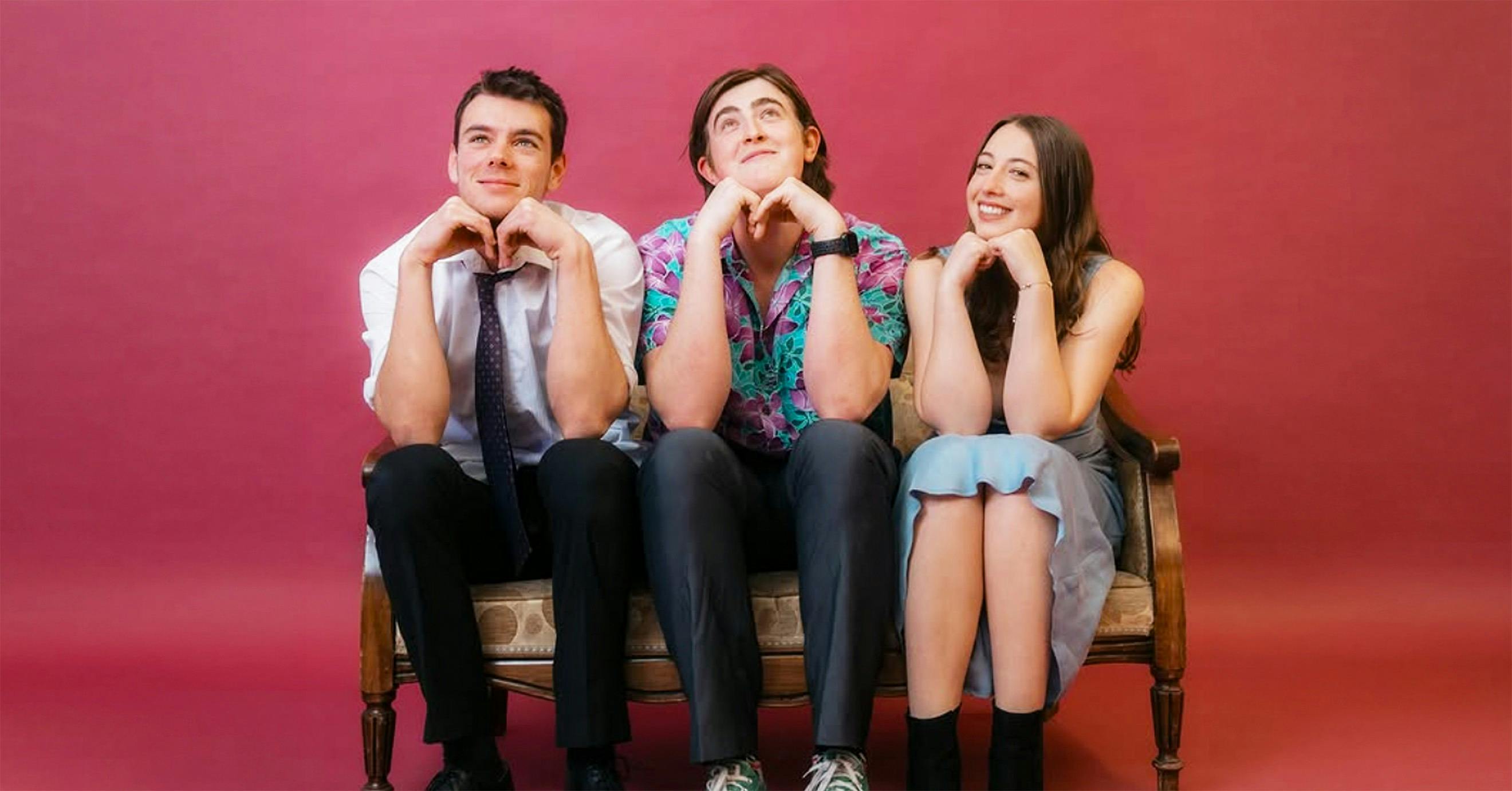 3 band members from Fathom, two men and a woman, sitting with their hands under their chins