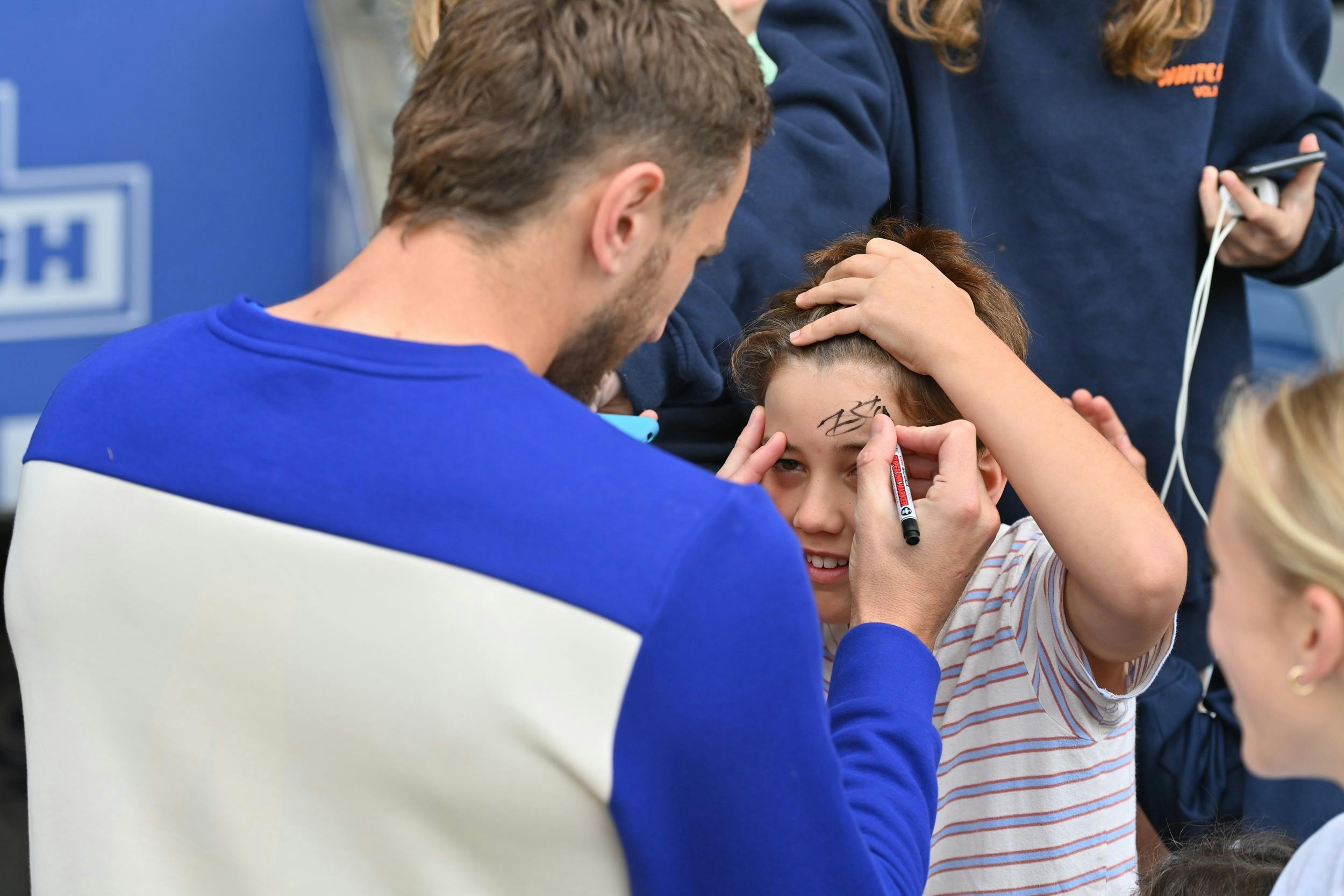 A football player signing a child's forehead.