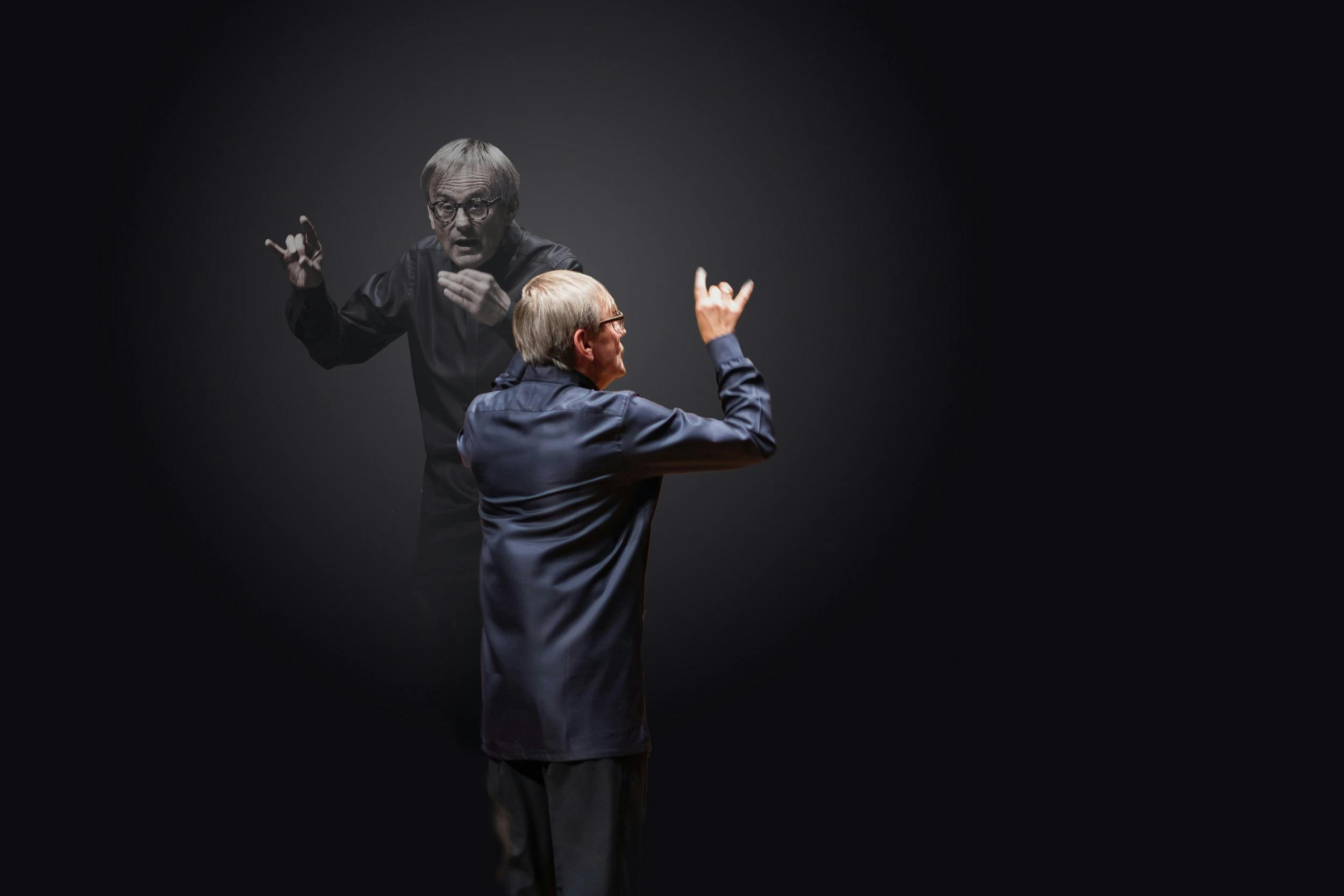 Conductor Simon Halsey is shown from behind with arms raised in a conducting gesture.
