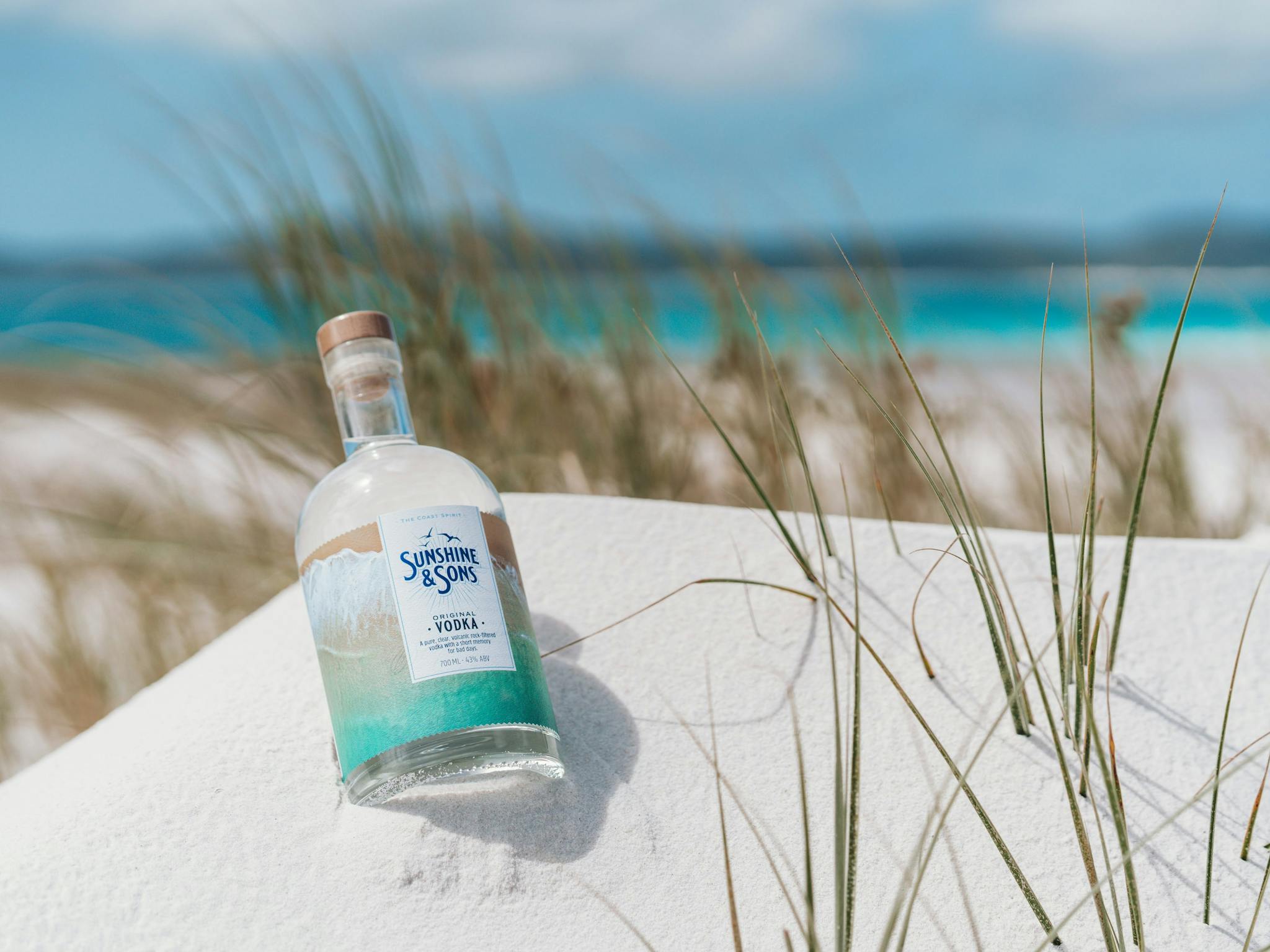 A bottle of our Original Vodka lying in white sand on the beach A bottle of our Original Vodka lying in white sand on the beach