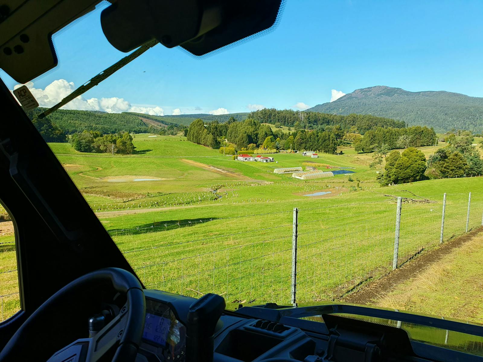View from front seat of ATV looking over green paddocks with Mt Arthur in background