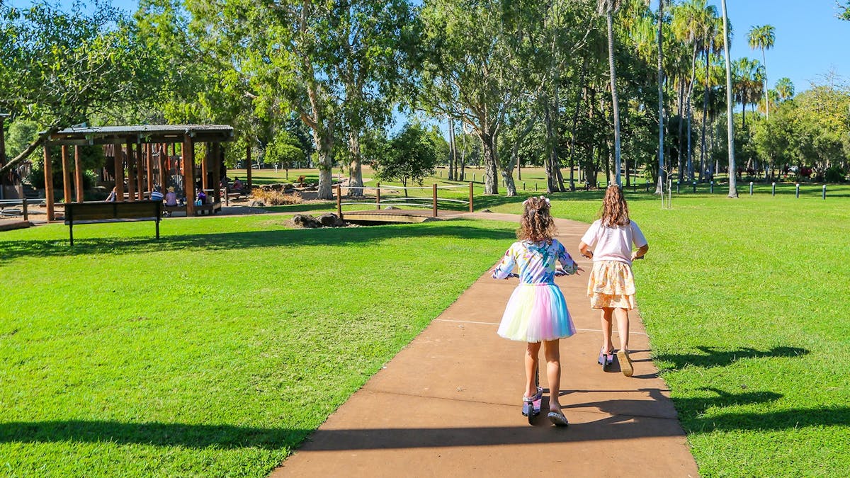 Two girls riding scooters in Plantation Park