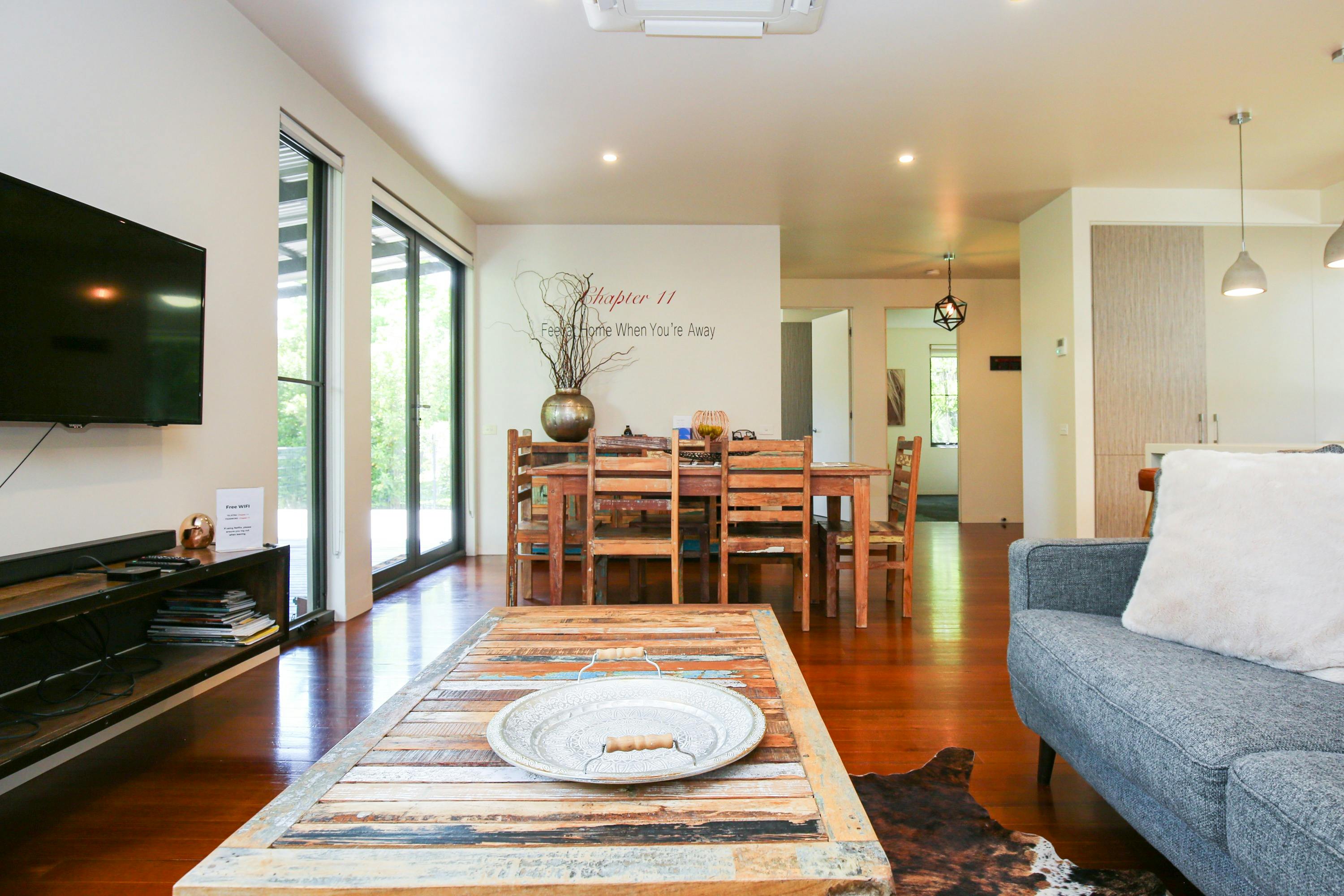 Lounge Room with couch, television, centre table and dining area in the background