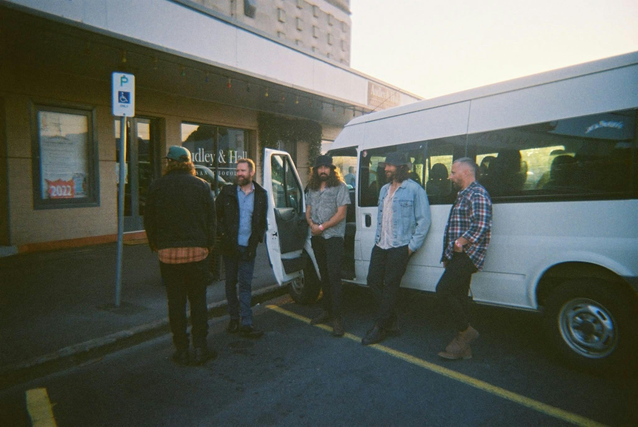 a band pictured standing in front of a van