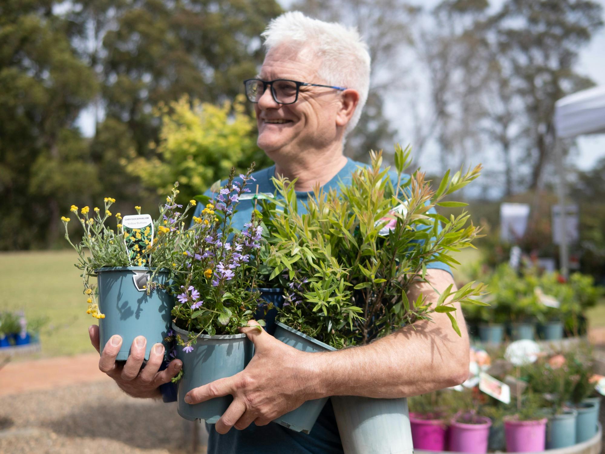 A man holding a large armful of native plants at the plant sale.
