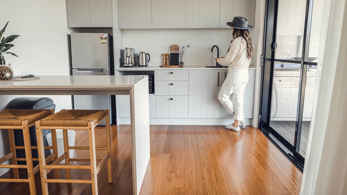 Breakfast bar with stools, kitchenette with lady preparing a drink