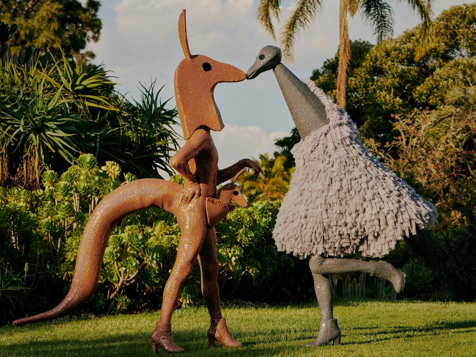 Two people pose in glittery costumes - one is a kangaroo and one is an emu