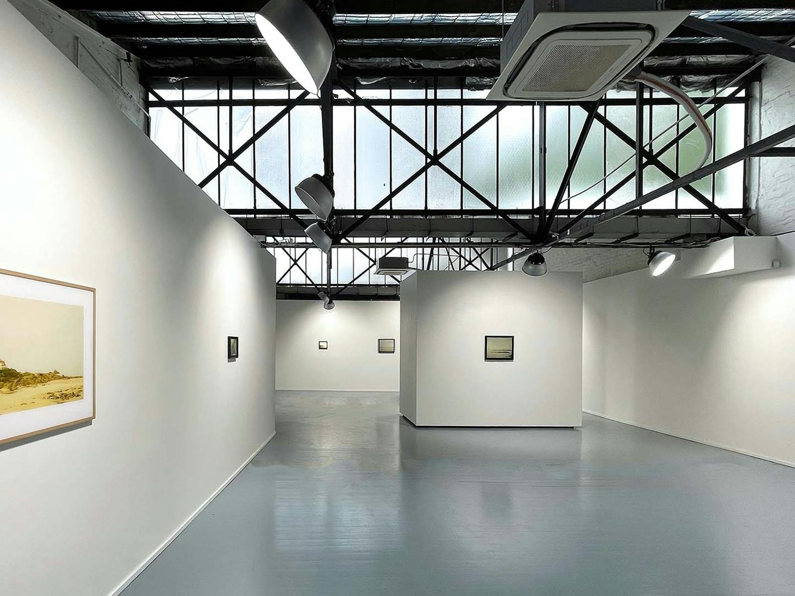 Interior shot of a gallery space, with naturally lit white walls and a high ceiling.