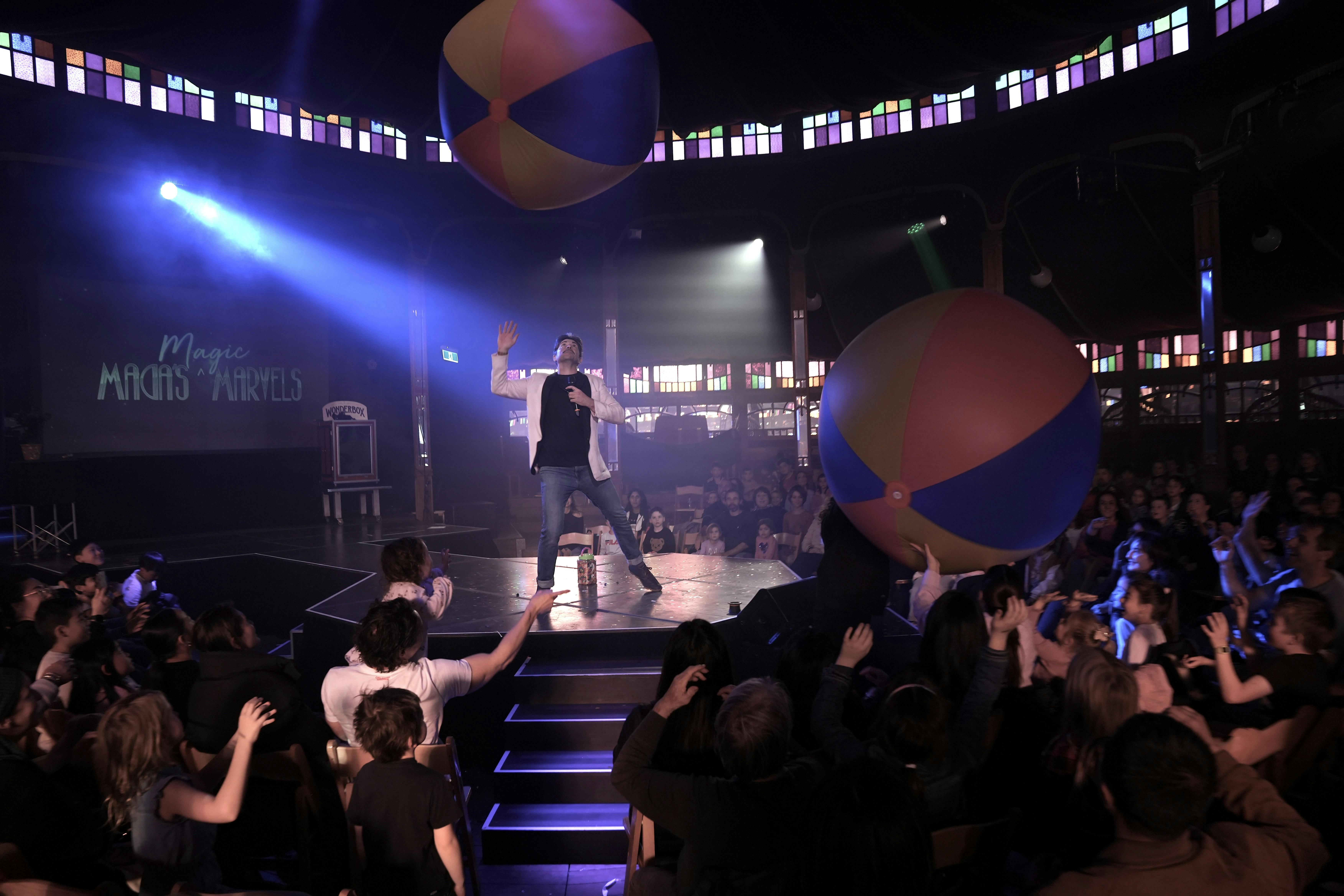 Adam Mada with giant inflatable beach balls flying through the audience.