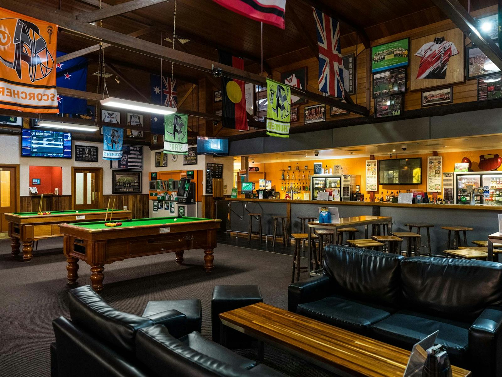 Bar filled with couches, high tables with stools, bar, TAB, pool tables & sports memorabilia