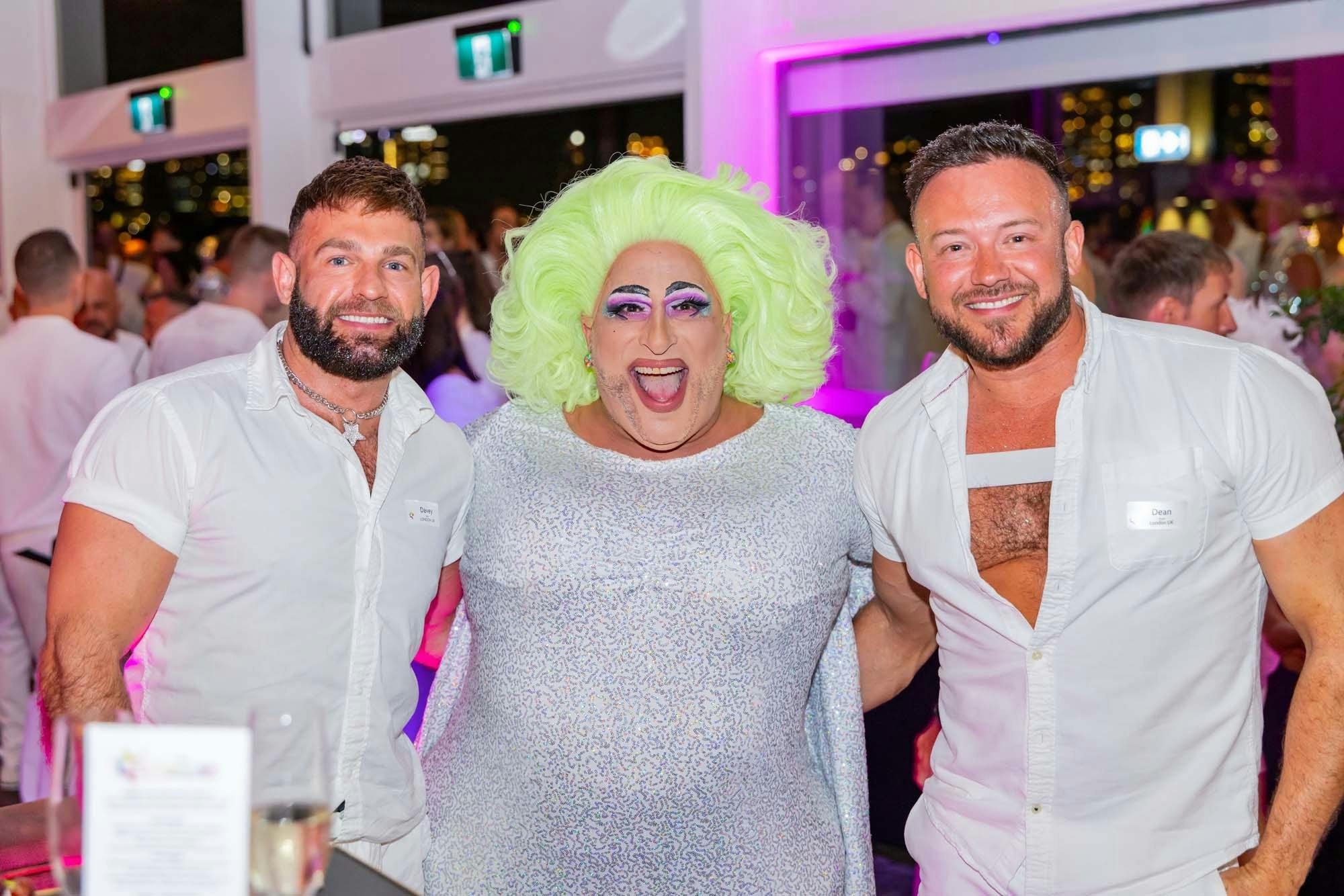 Drag entertainer Frock Hudson posing with two guests in white at Celebration NYE.
