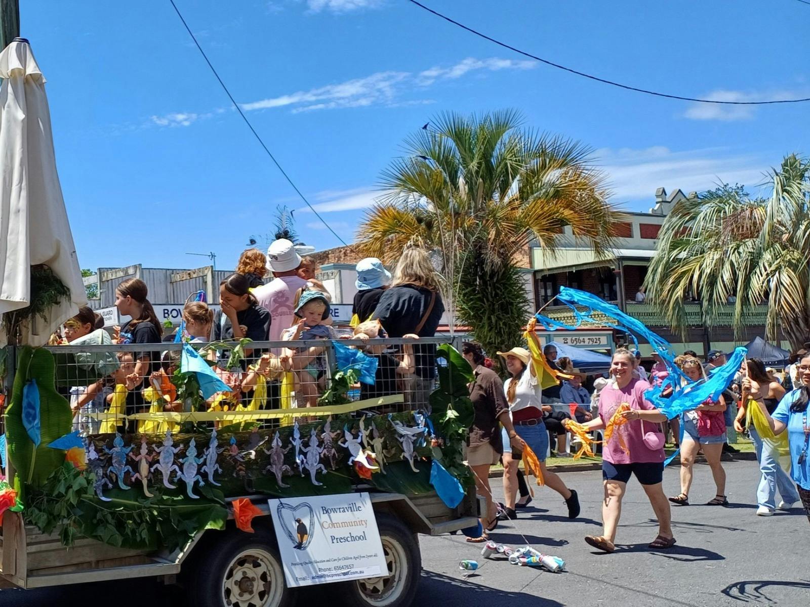 Children waving and smiling to the crowd as the parade passes down the main street