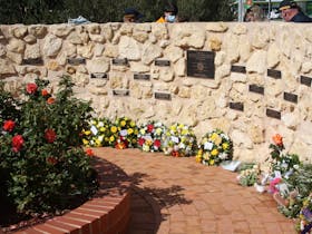 A curved stone wall adorned with name plates of South Australian Fire-Fighters lost on duty