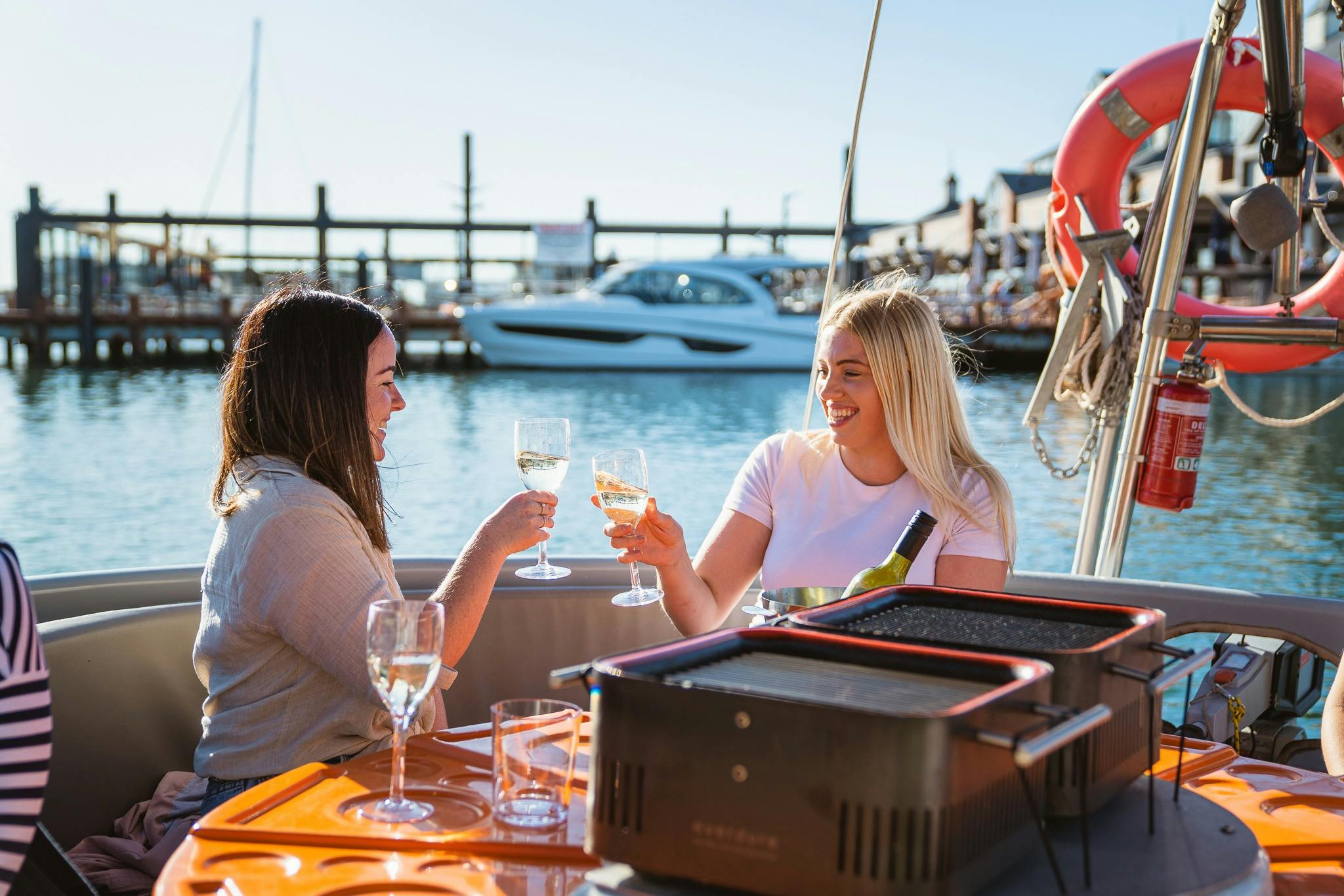 2 girls clinking glasses  on bbq boat