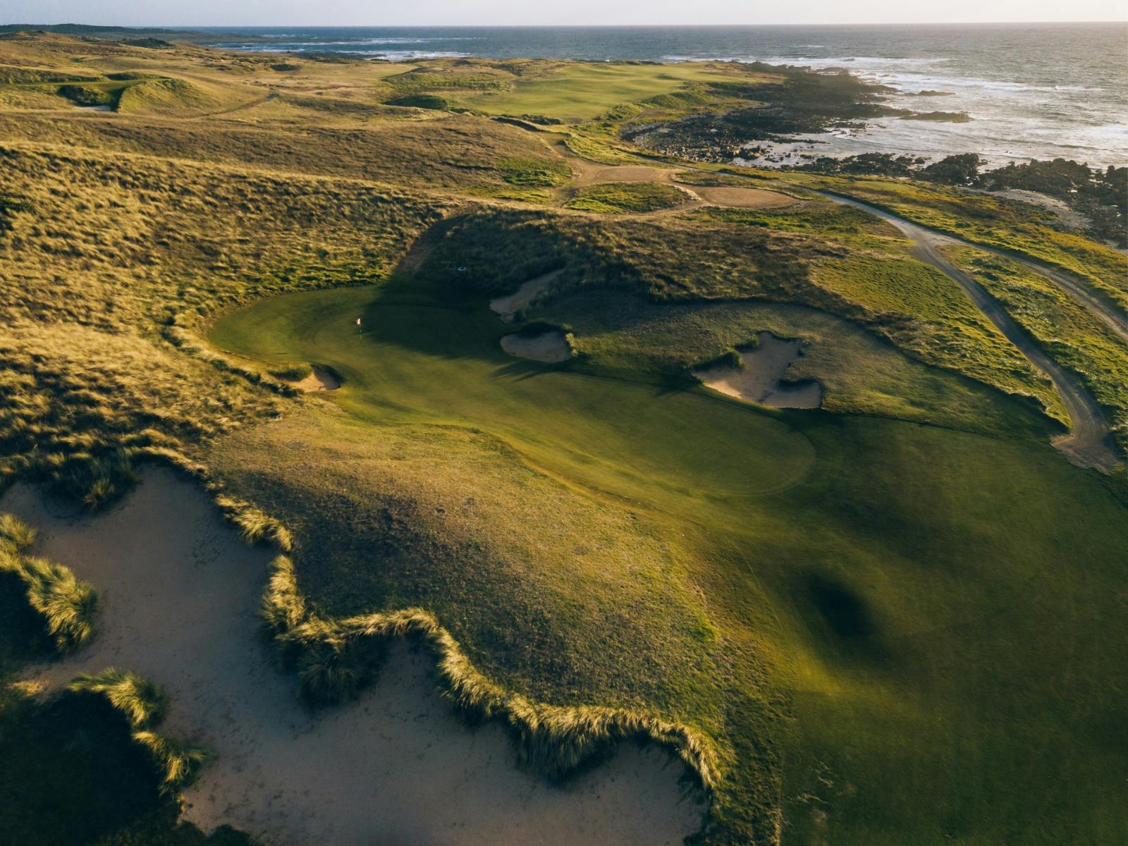 Aerial view of coastal fairway and green surrounded by dunes at Ocean Dunes Golf Course