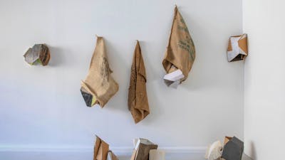 Series of hessian sacks, packaging cardboards, plaster and other materials on a wall.