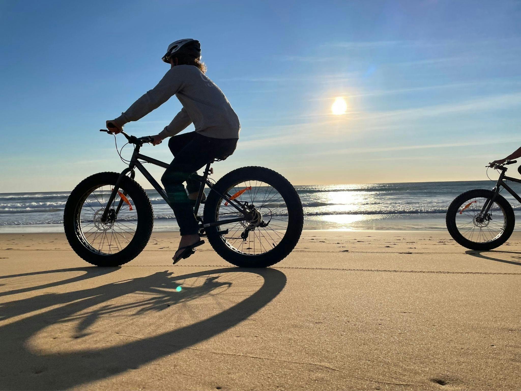 Fat tyre bike riding on sandy beach.