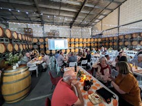 Crowd of people sit in barrel hall with fairy lights