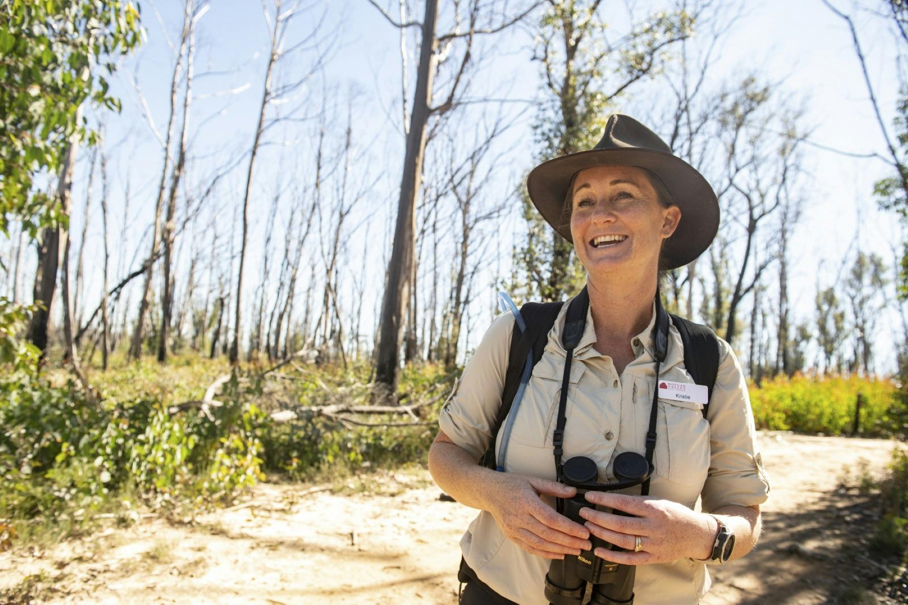 Our welcoming local guide smiling wearing a wide brimmed hat and holding a pair of binoculars