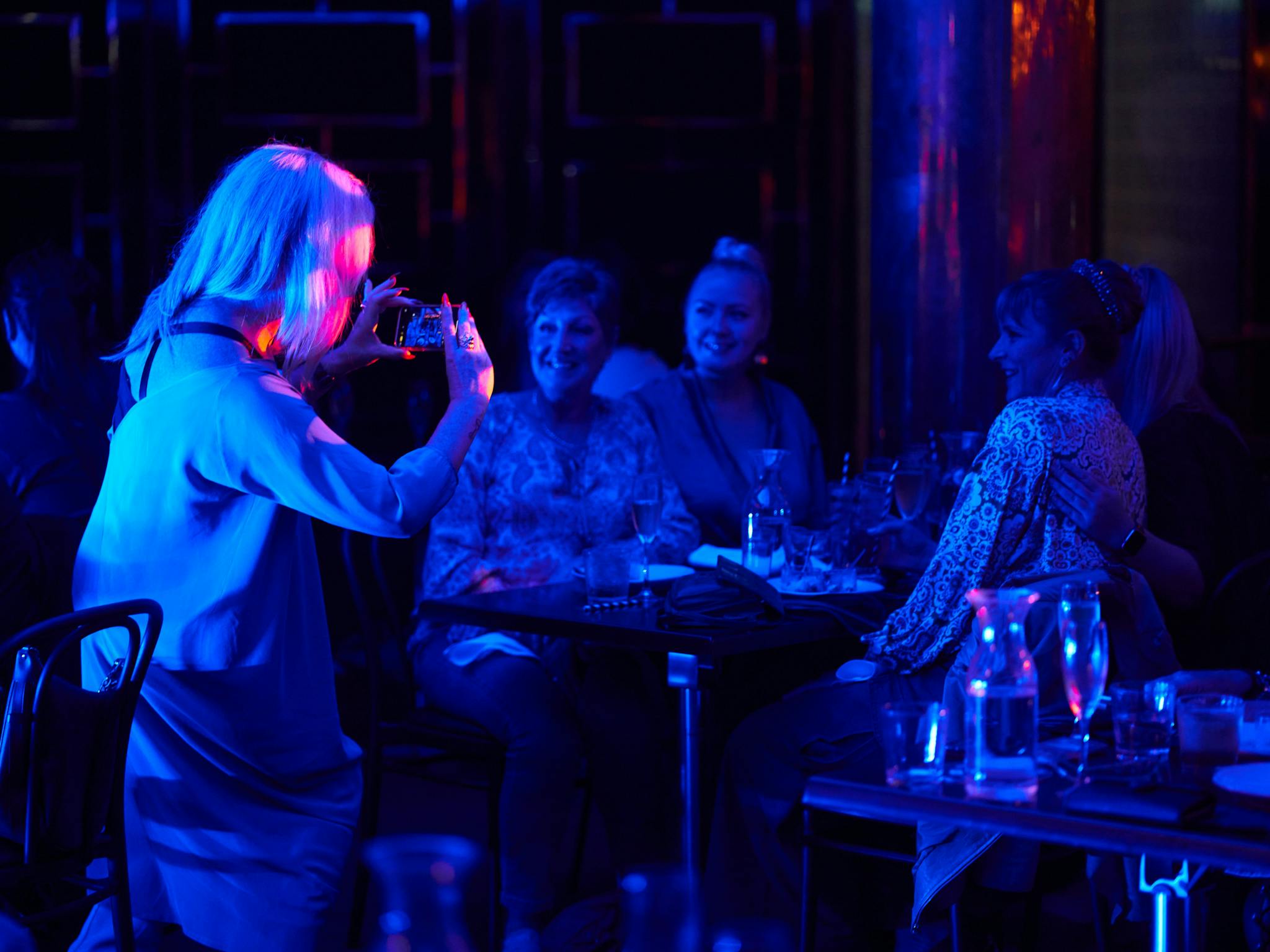 A group of mature women laugh, eat, drink and take selfies in this dinner show.