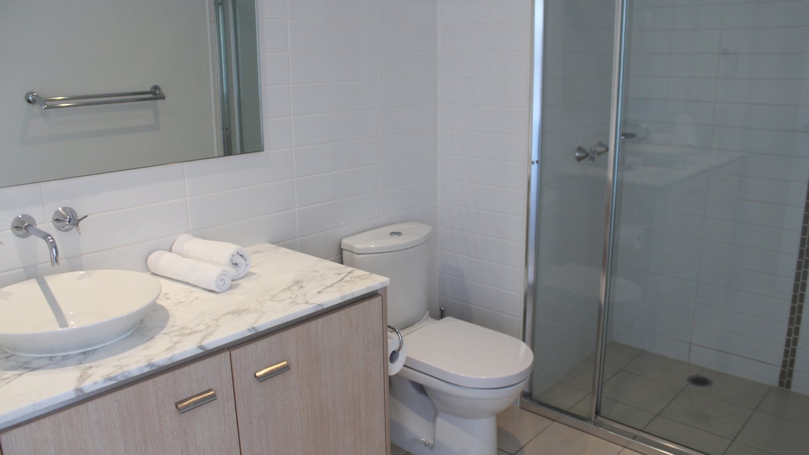 Studio apartment bathroom with walk in shower, toilet, and bathroom sink