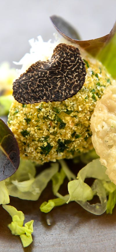 An image of a black plate with antipasto roulade on a white background.
