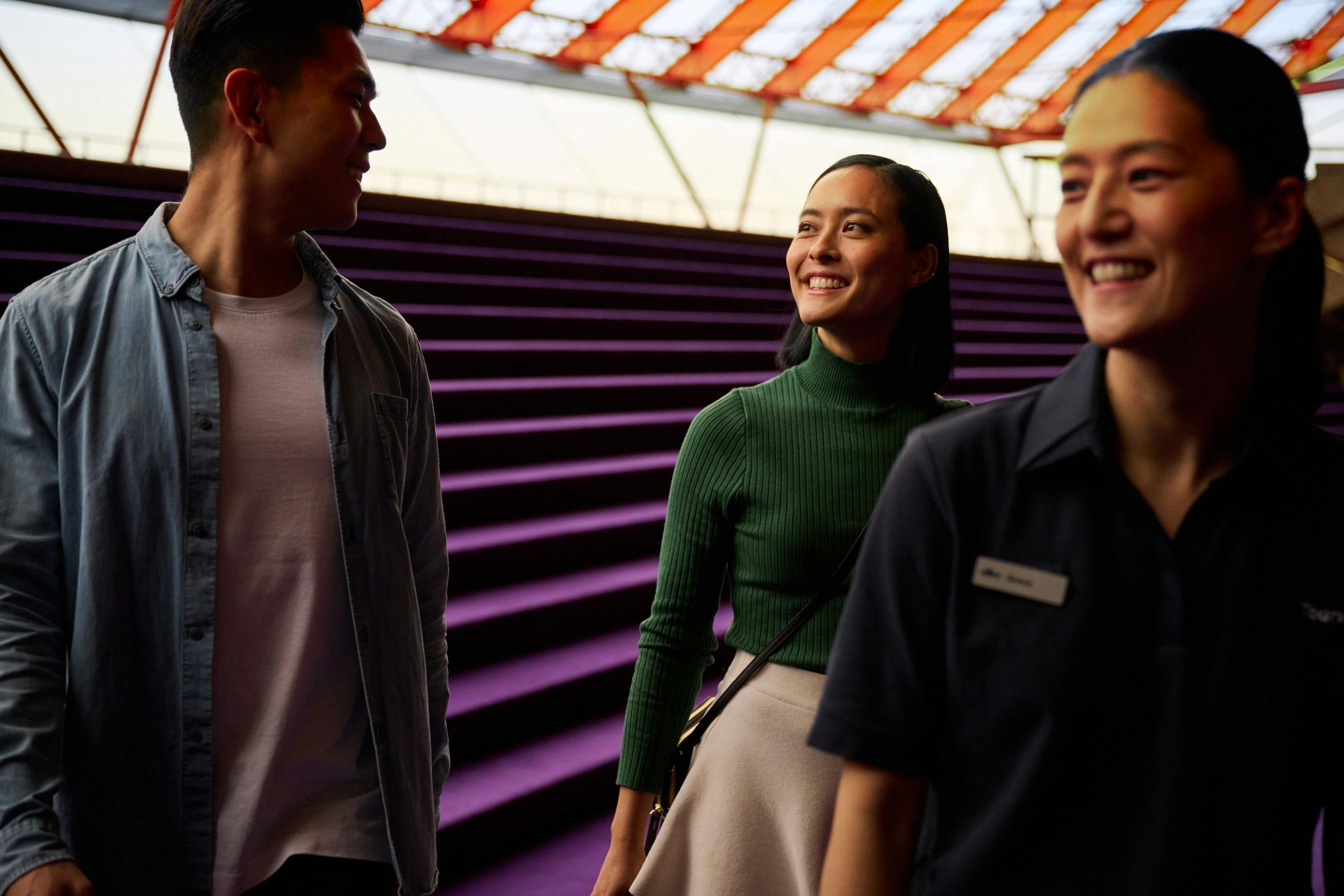 Tour guide leading man and woman down the purple steps in the Concert Hall Northern Foyer