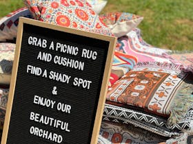 An invitation to enjoy the orchard with rugs and cushions
