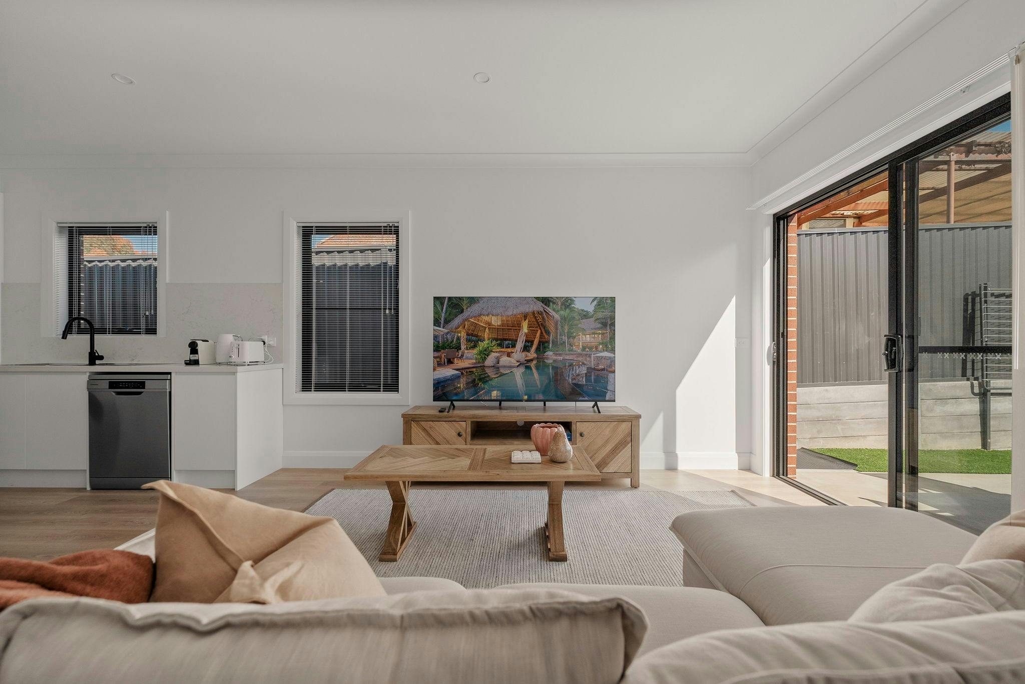 Living room with large L shaped couch, large sliding windows & doors and open to the kitchen area