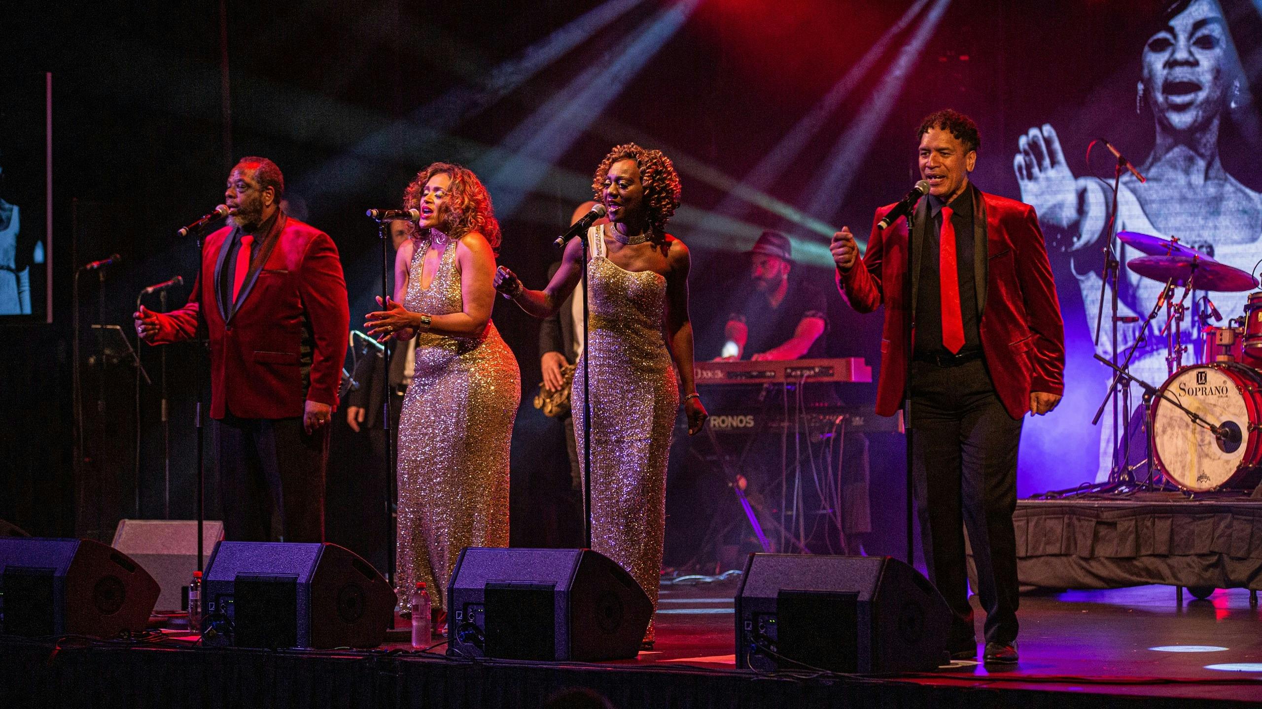 Band on stage for singers and man with keyboard in the background